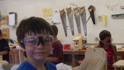 camper posing with finished birdhouse made in the camp wood shop
