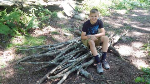Youth sitting on a raft made out of sticks. 