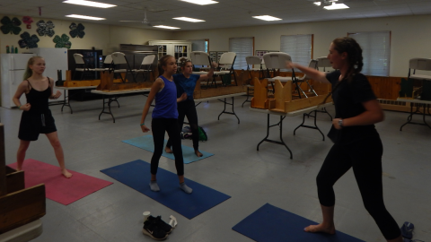 small group of campers standing doing yoga with counselor.